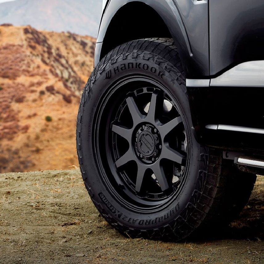 A close up of a black wheel on a white background.