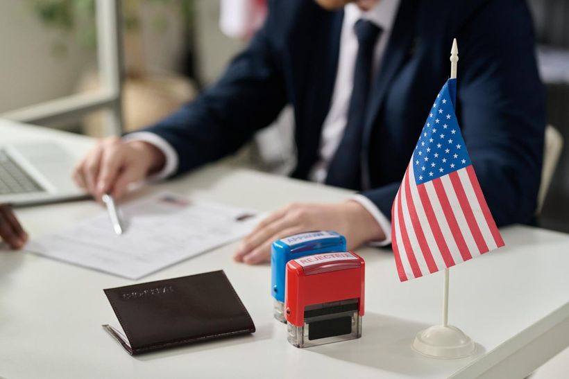 Business meeting desk with U.S. flag, papers, stamps, and laptop in a professional office