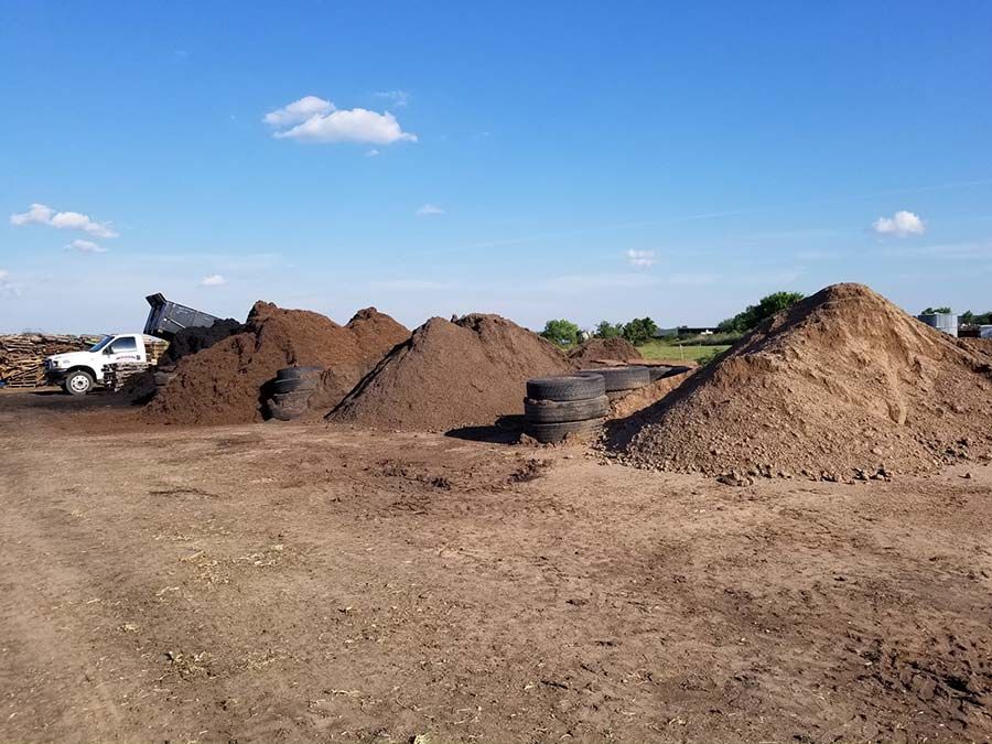 A pile of dirt and tires in a field with a truck in the background.