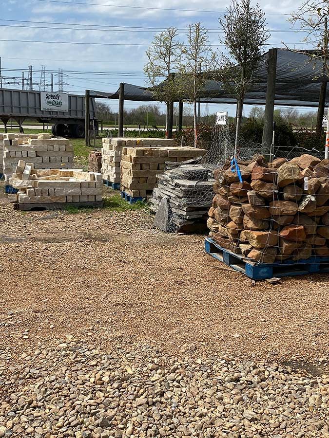 A pile of rocks and bricks on pallets in a gravel lot.