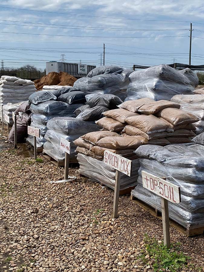 A bunch of bags of soil are stacked on top of each other in a pile.