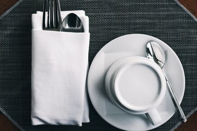 Alzata di legno a più livelli con vari tagli di formaggio, sormontata da una ciotola decorativa in legno, su un tavolo bianco.