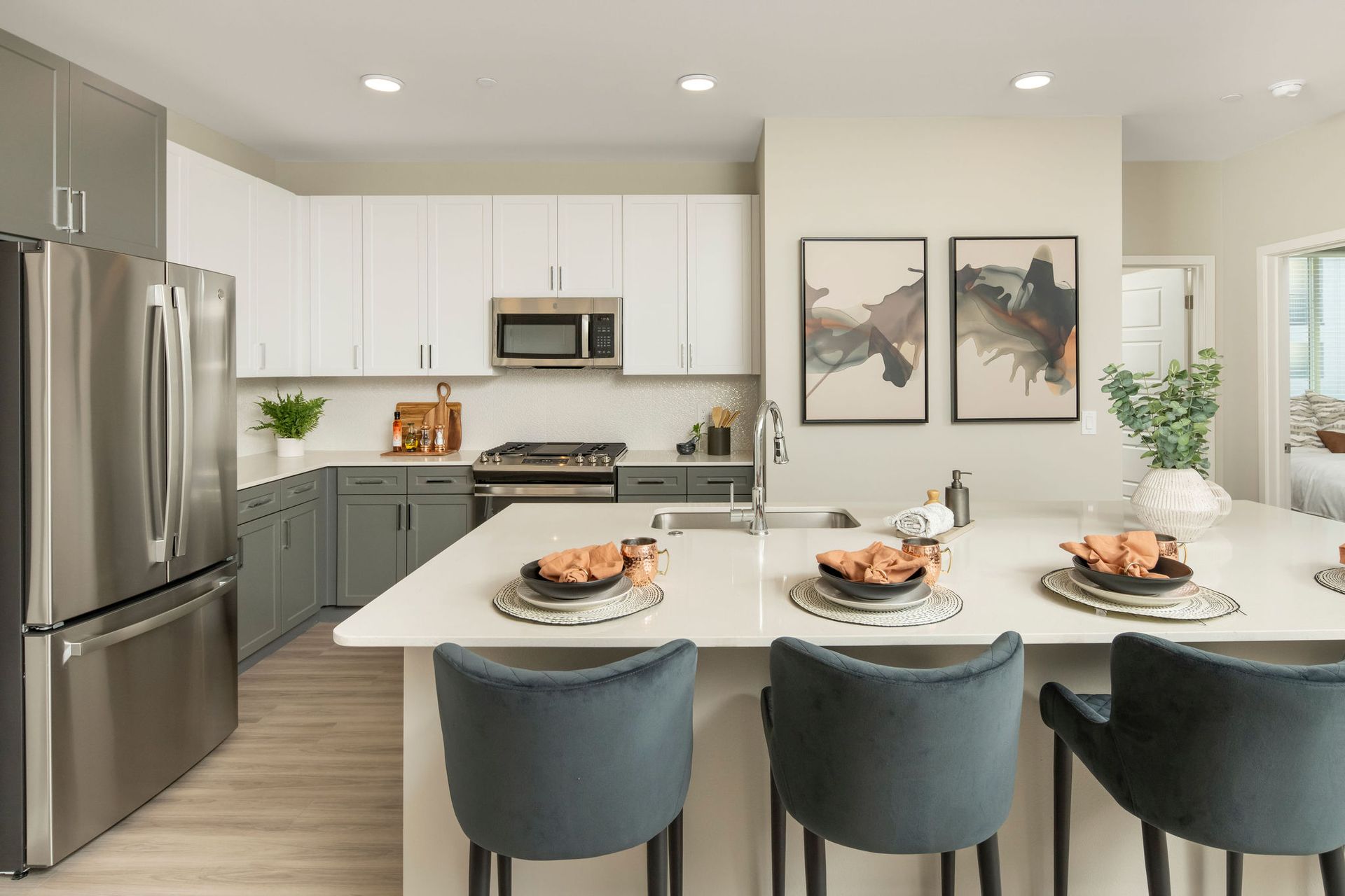 Modern kitchen with white upper cabinets, gray lower cabinets, stainless steel appliances, and an island with seating.