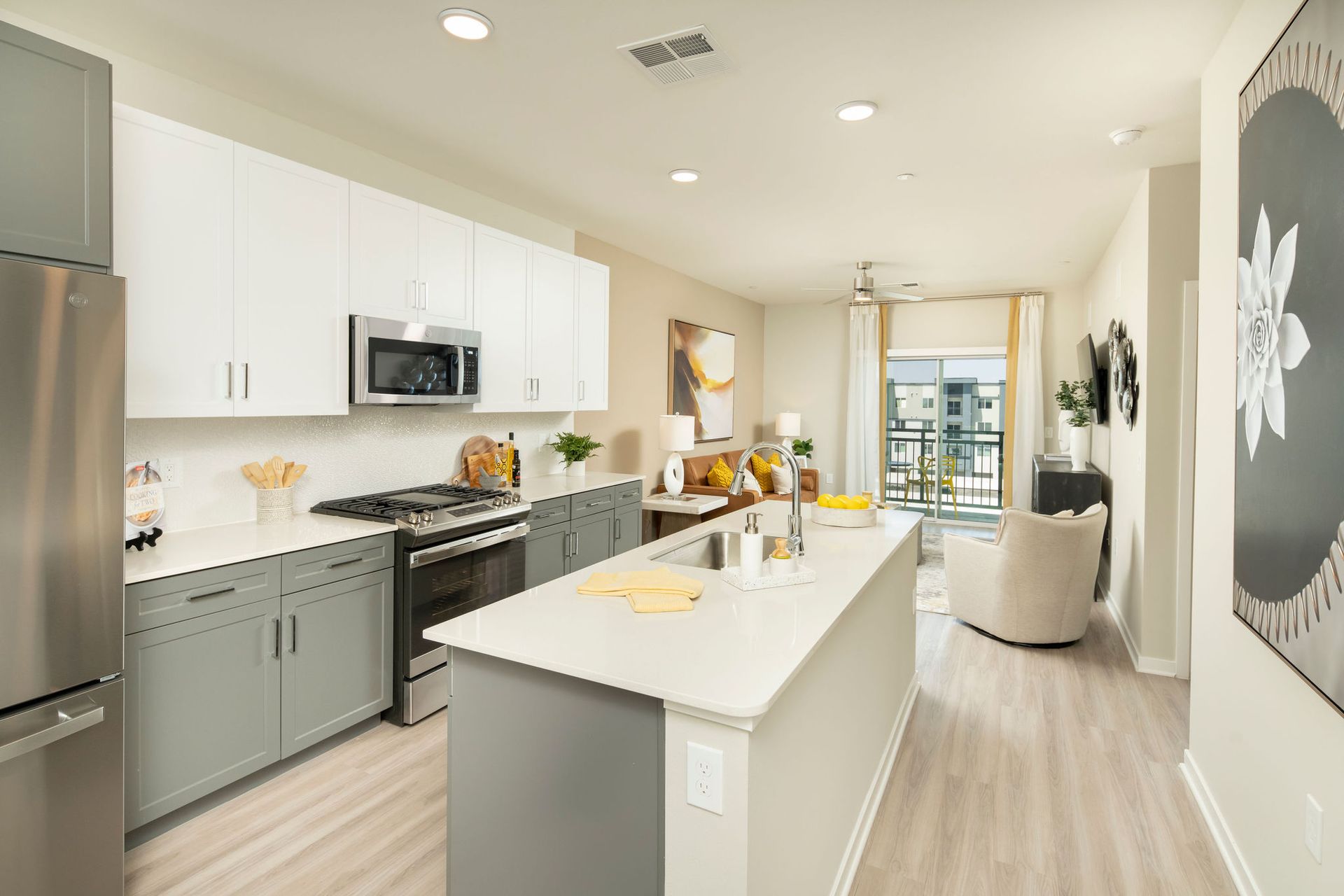 Open-concept kitchen and living area in a modern apartment with an island and stainless appliances.