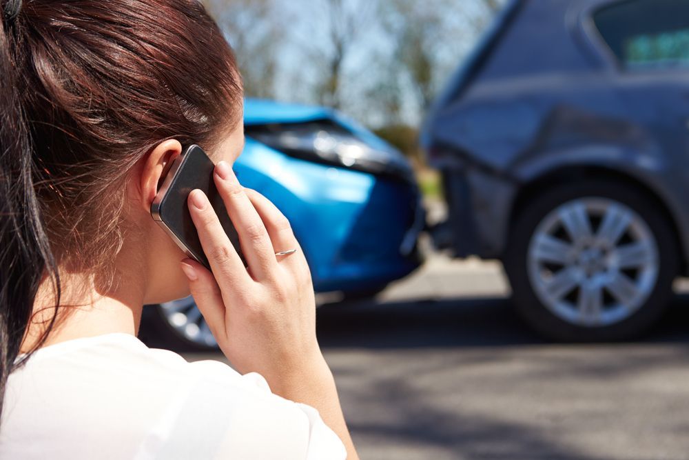 A Woman is Talking on a Cell Phone in Front of a Car Accident — Crossborder Towing in South Albury, NSW
