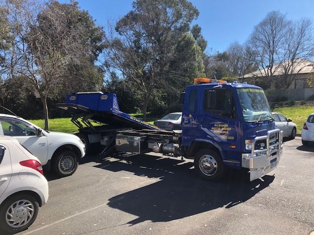 A Blue and Yellow Tow Truck is Parked in Front of a Building — Crossborder Towing in Thurgoona, NSW
