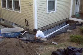 A man is sitting on the ground in front of a house.