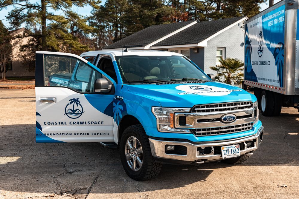 Coastal Crawlspace work vehicles parked in front of a house.