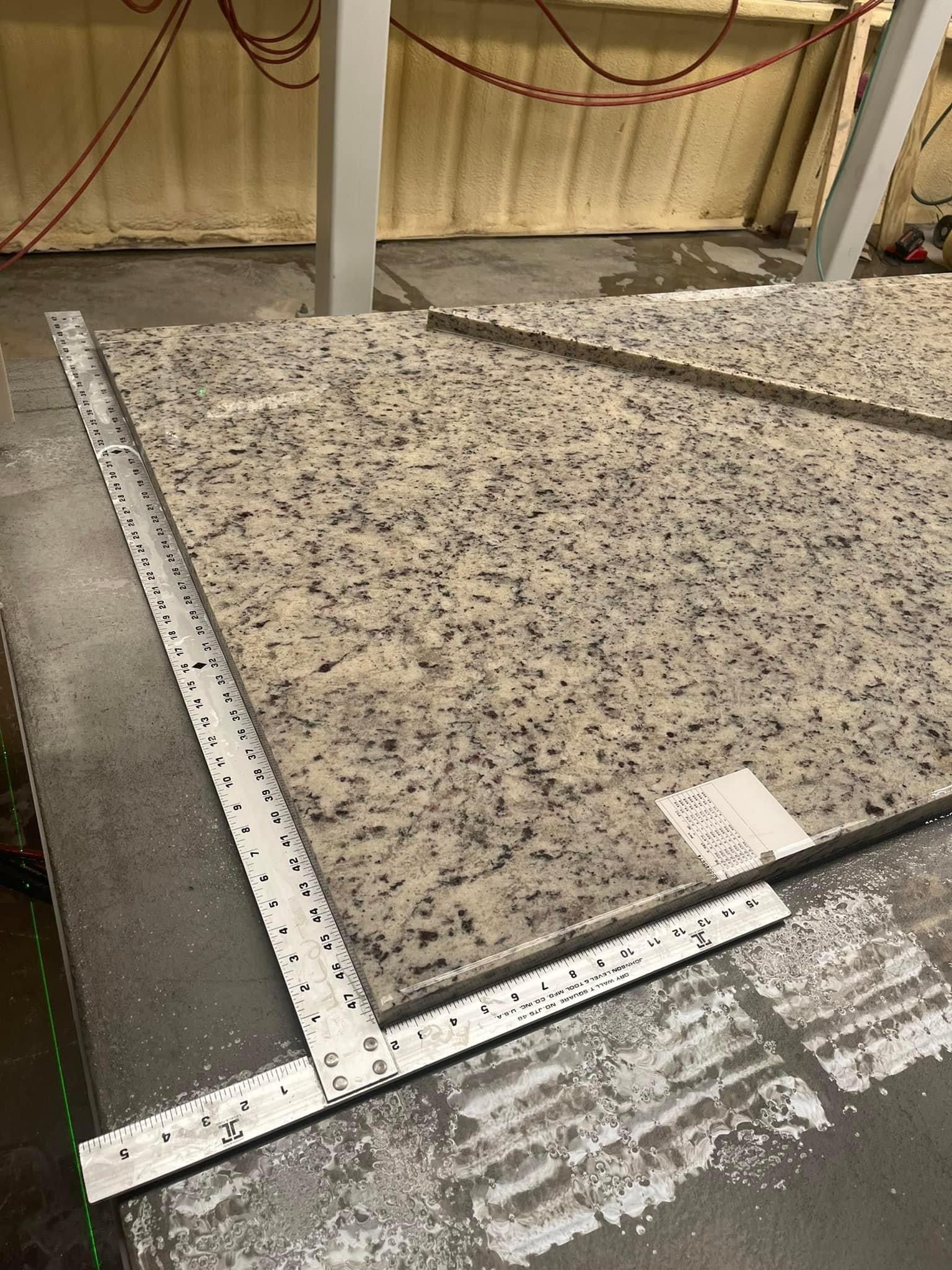 Granite slab with measuring tools on a gray surface in a workshop.