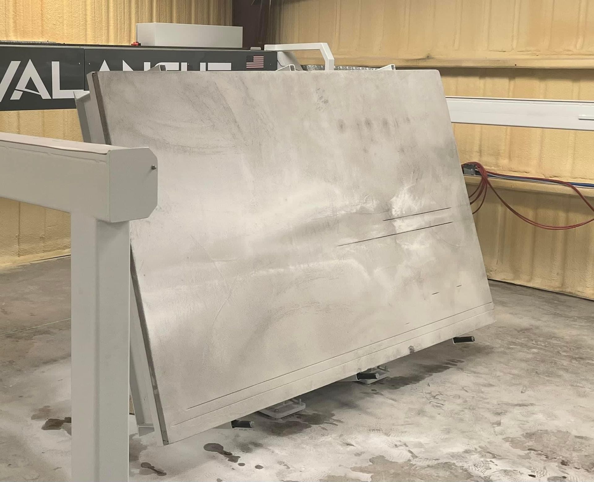 Large slab of metal being cut by an industrial machine inside a workshop.