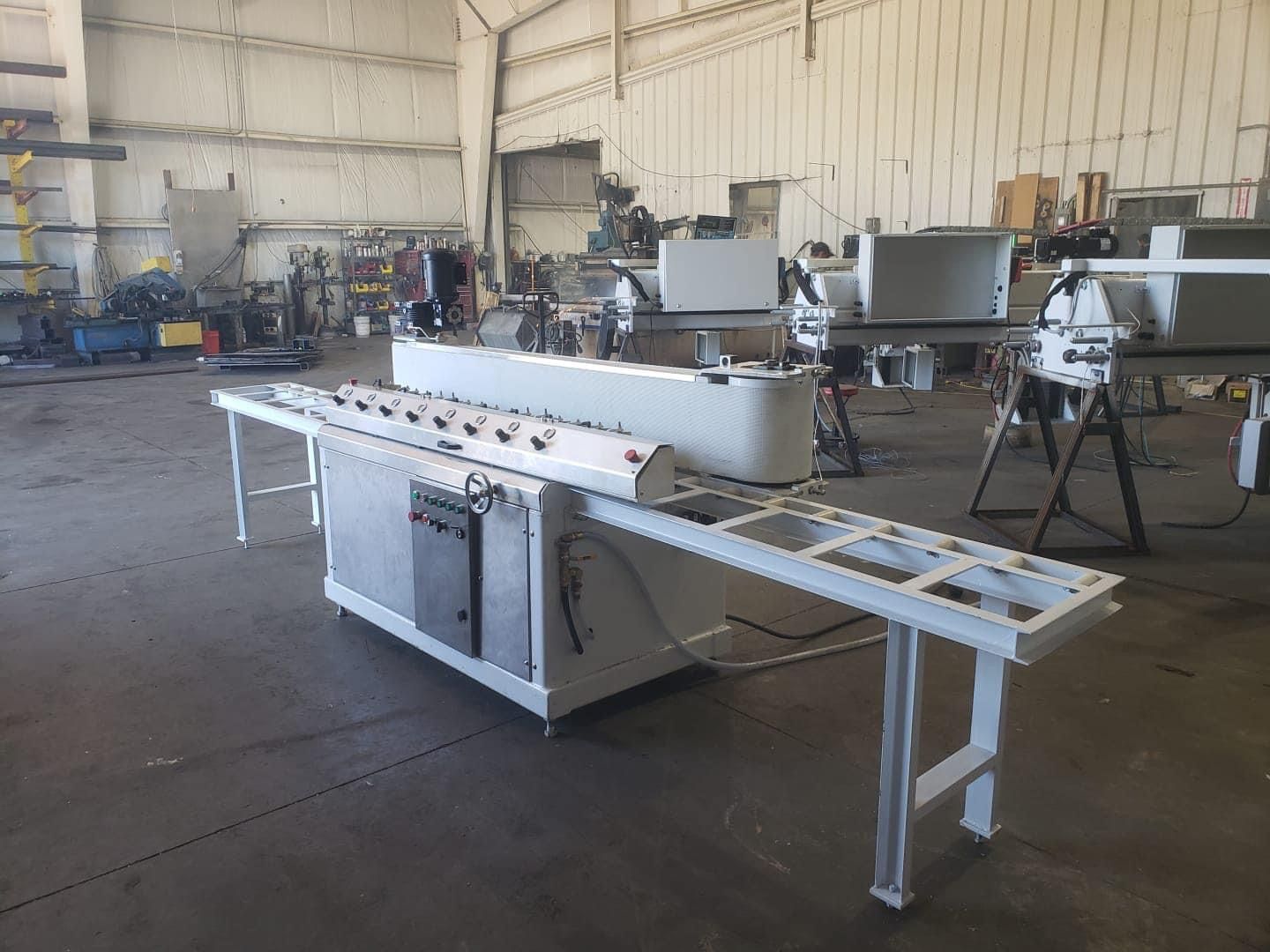 A large industrial machine with a control panel and tables in a workshop.