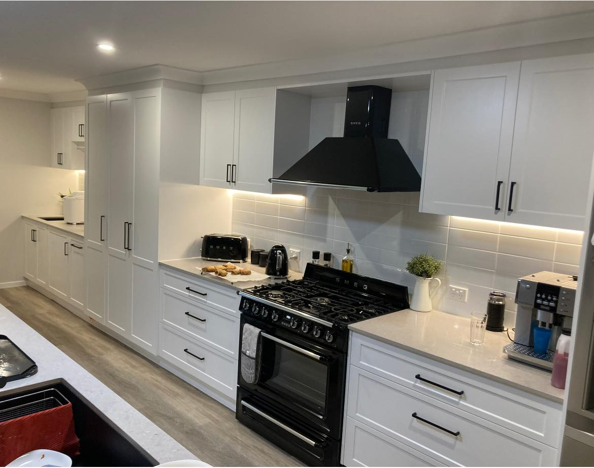 A kitchen with white cabinets and a black stove top oven. — Short Stop Electrical in Nerang, QLD