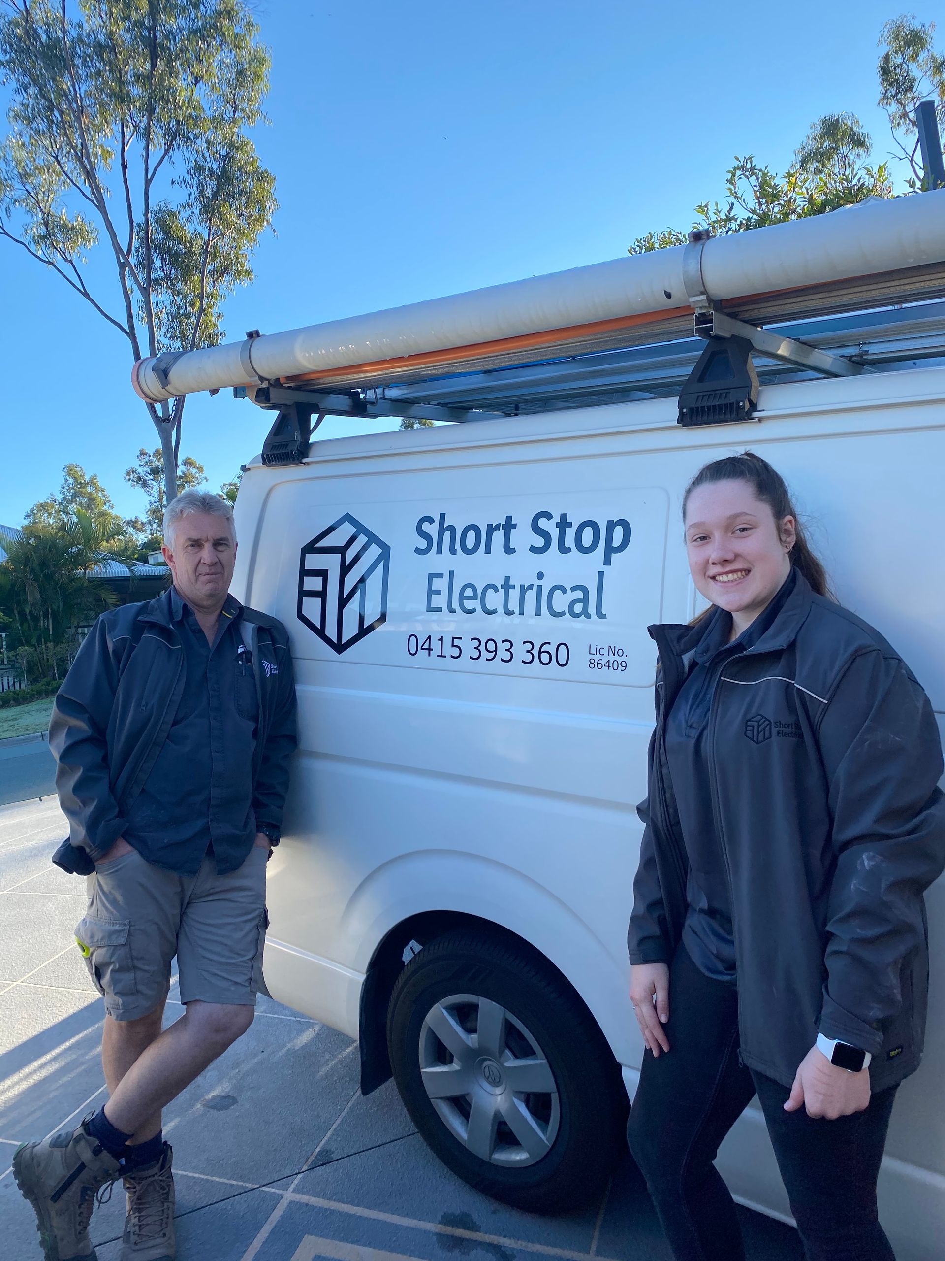A Man And A Woman Are Standing Next To A Short Stop Electrical Van — Short Stop Electrical in Nerang, QLD