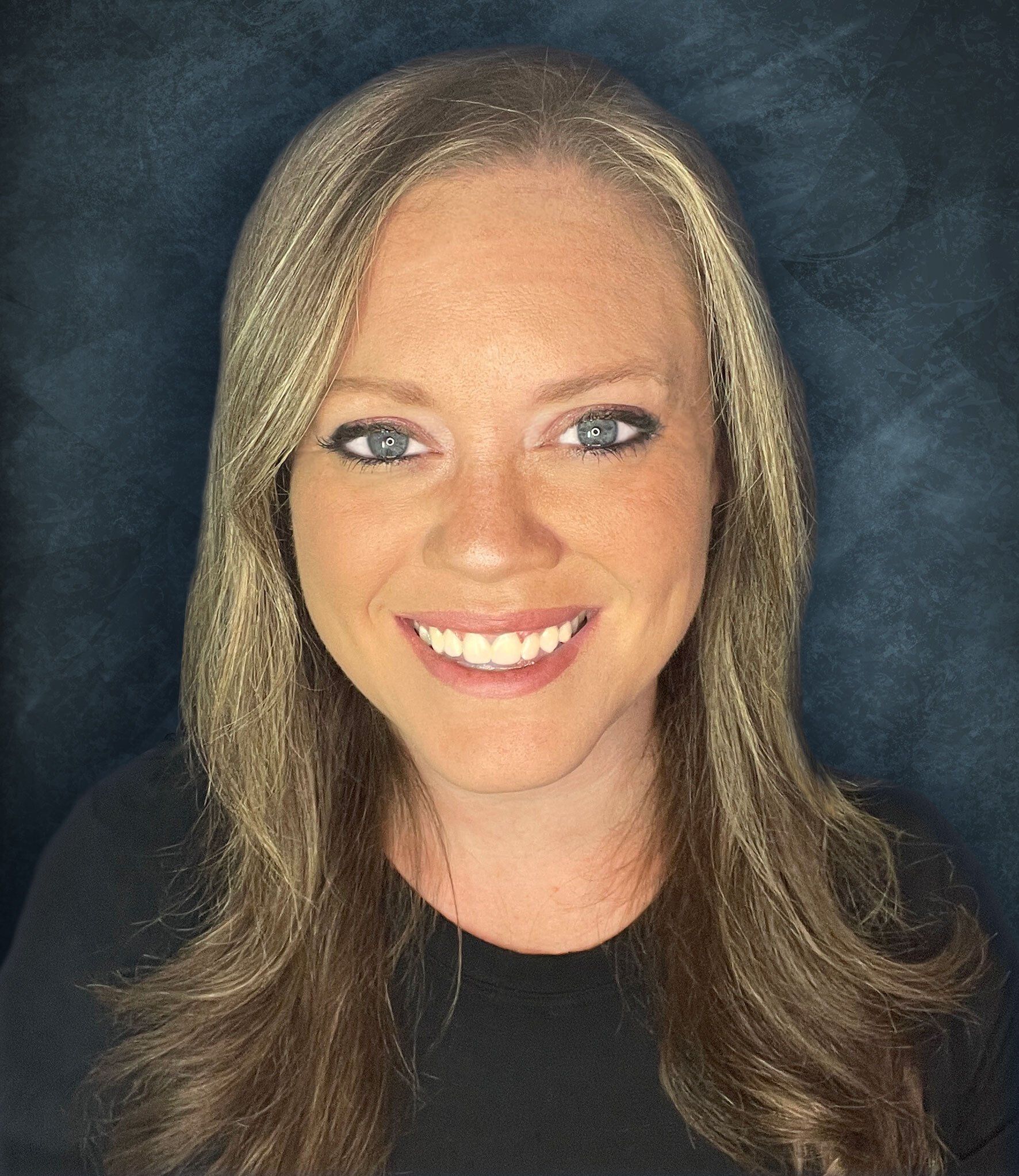 A woman with long hair is smiling and wearing a black shirt.