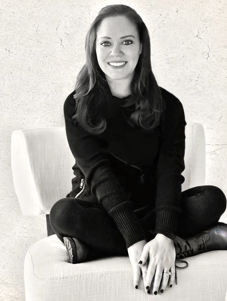 Woman seated, smiling, wearing black, on white chair.