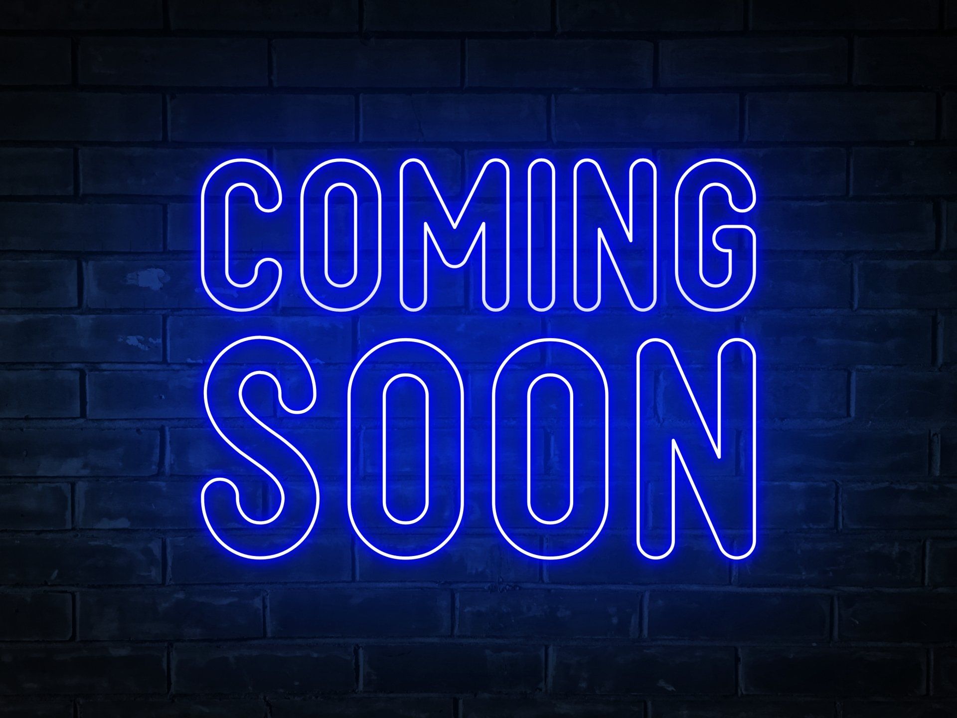 A neon sign that says `` coming soon '' on a brick wall.