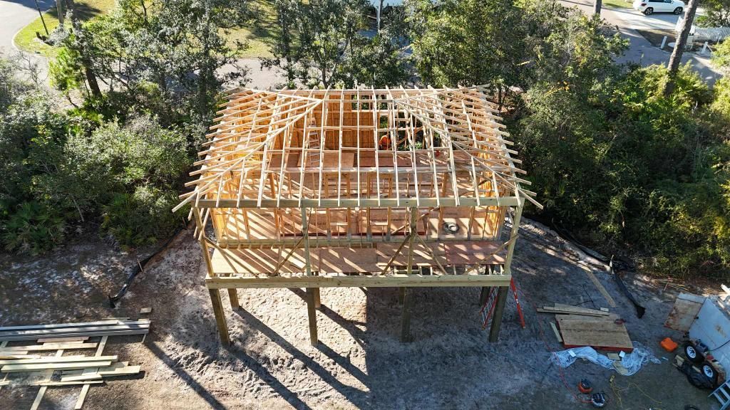 Wooden structure under construction, elevated on posts, with a domed roof frame.