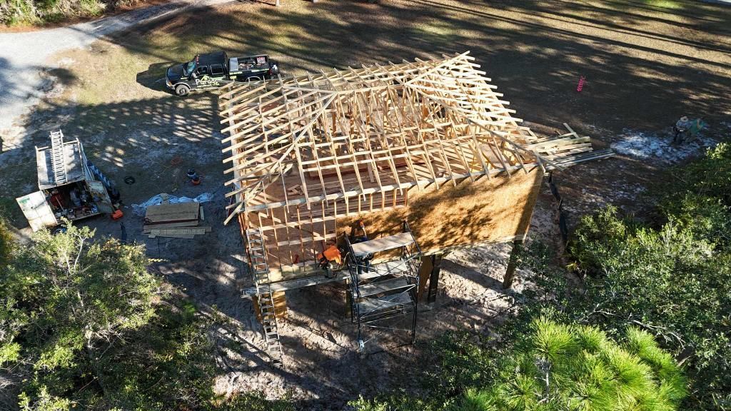 Aerial view of a building under construction, showing the exposed wooden frame and workers below.