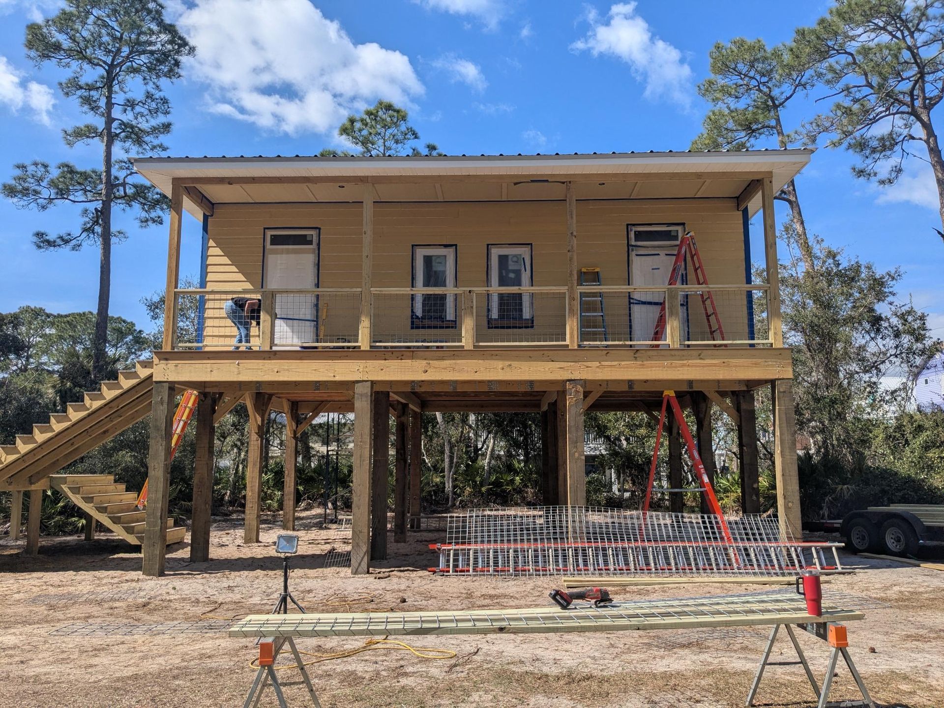 Two-story house on stilts under construction with stairs and a porch.