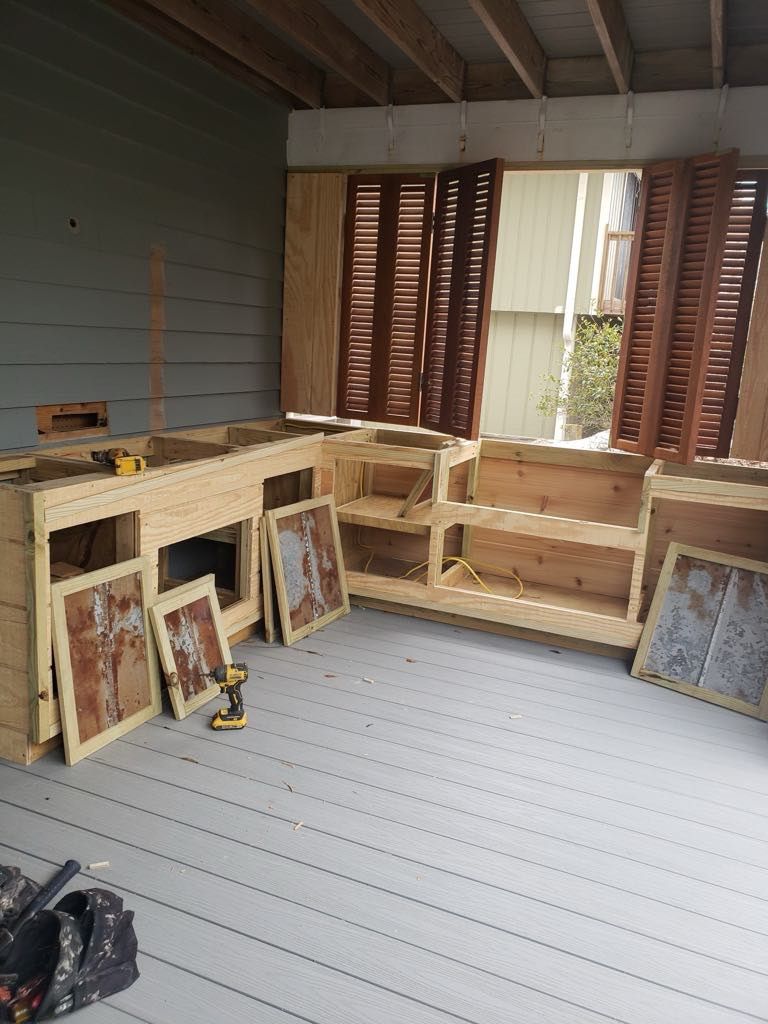 Wooden structure under construction on a deck with open shutter windows.