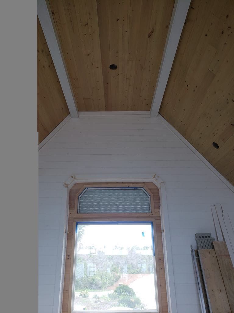 Interior view of a window and wooden ceiling. The ceiling is paneled with white trim and a recessed center.