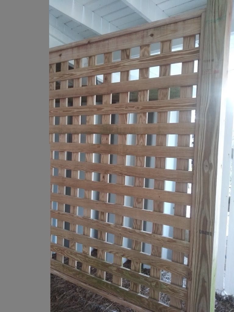 Wooden lattice screen, installed on a deck. Beige wood against a white background.