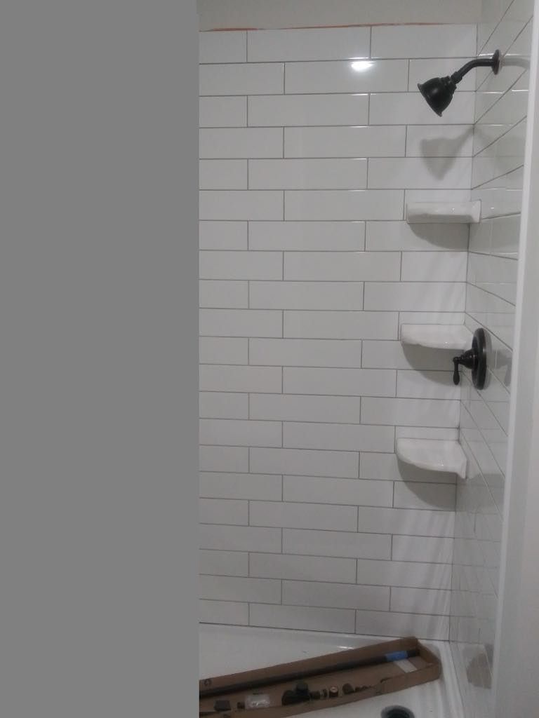White tiled shower with black fixtures and built-in shelves.