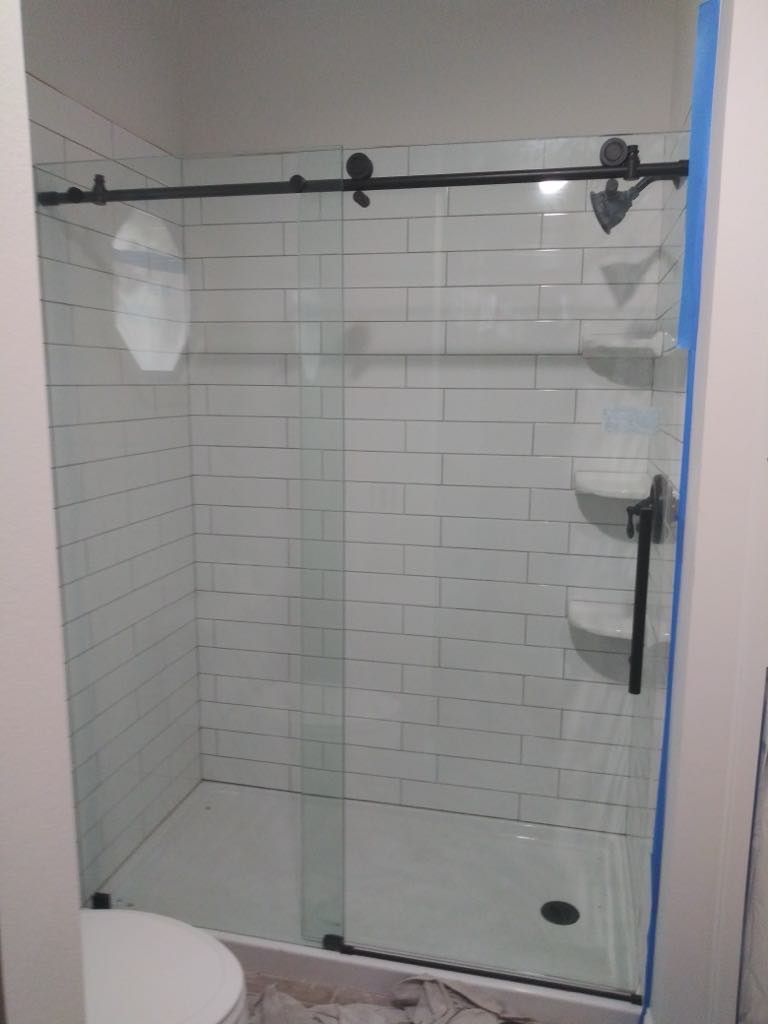 Shower stall with white subway tile, a sliding glass door, and black hardware.