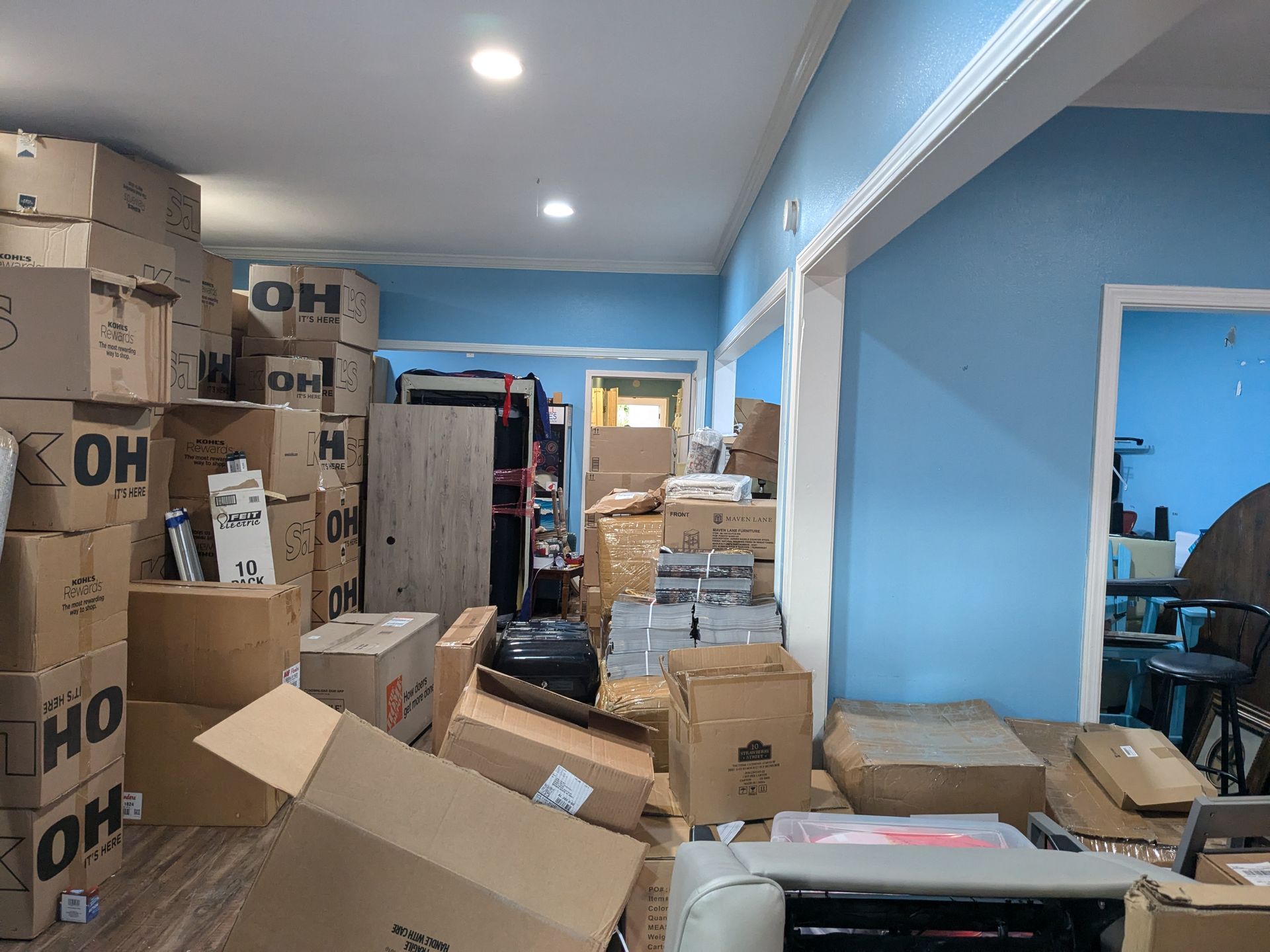 Interior cluttered with cardboard boxes in a light blue room.