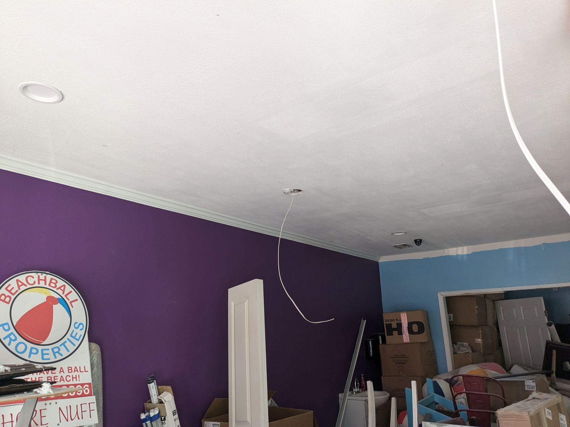 Purple and blue walls, ceiling with recessed lights, Beachball Properties sign, boxes.