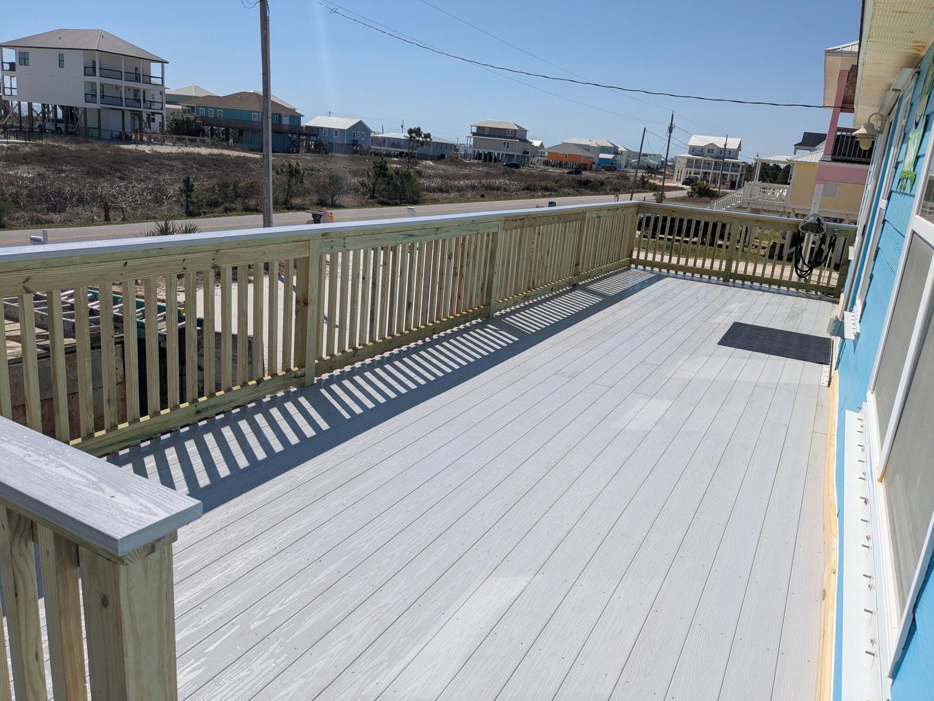 Wooden deck overlooking ocean, trees, and blue sky.