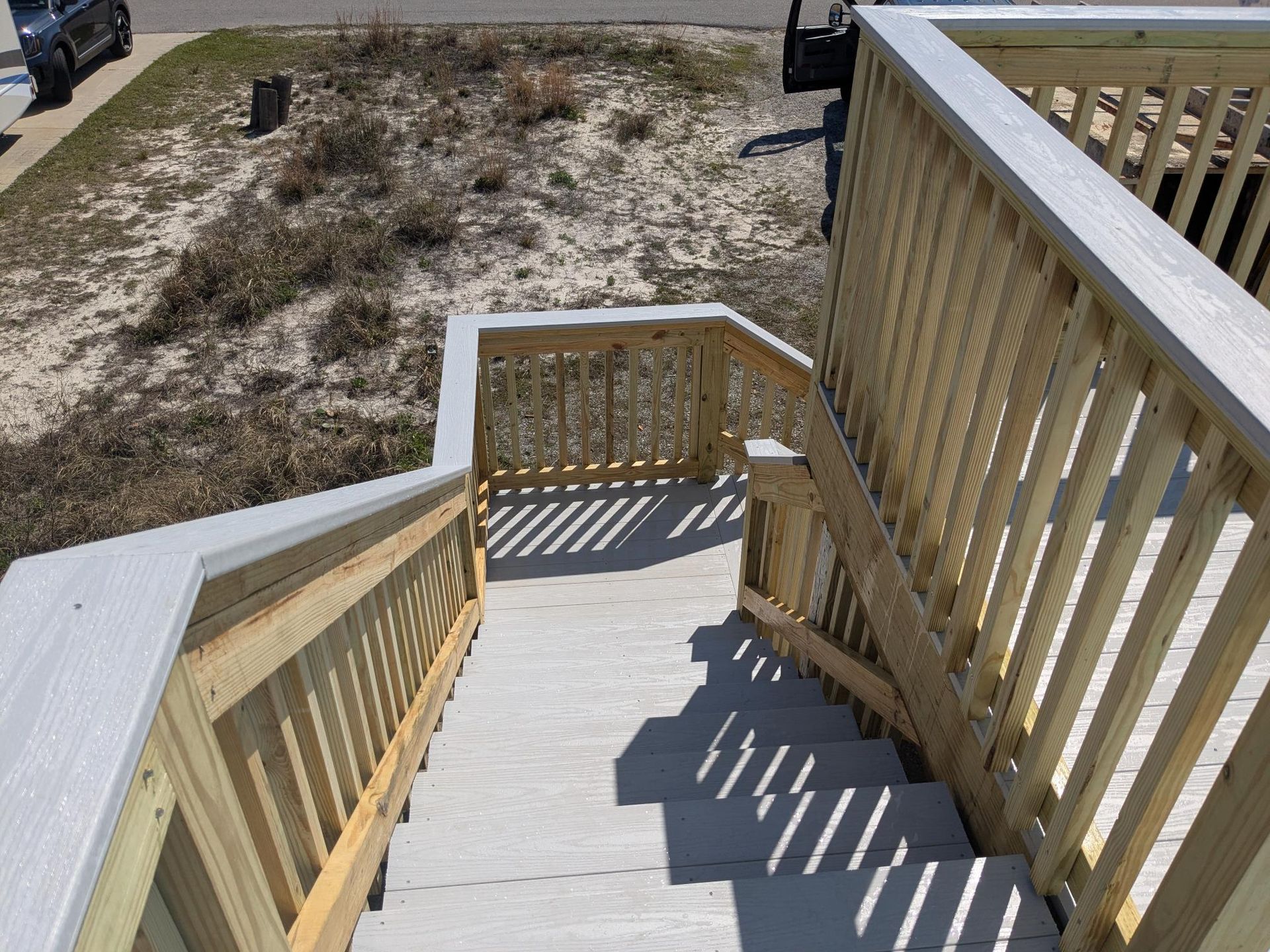 Wooden staircase leading down from a deck with railings.
