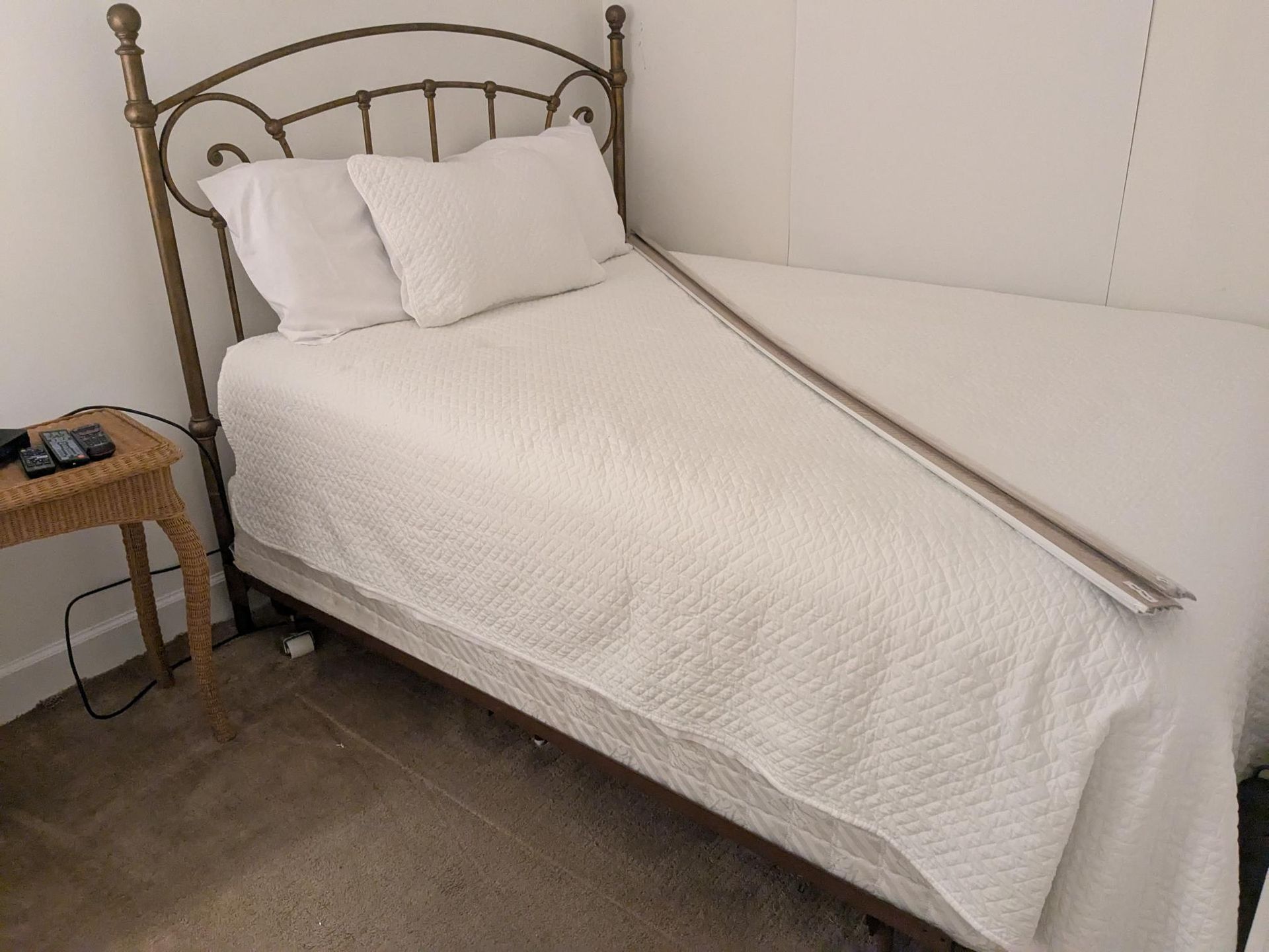 Bed with white bedding and metal frame; small side table.