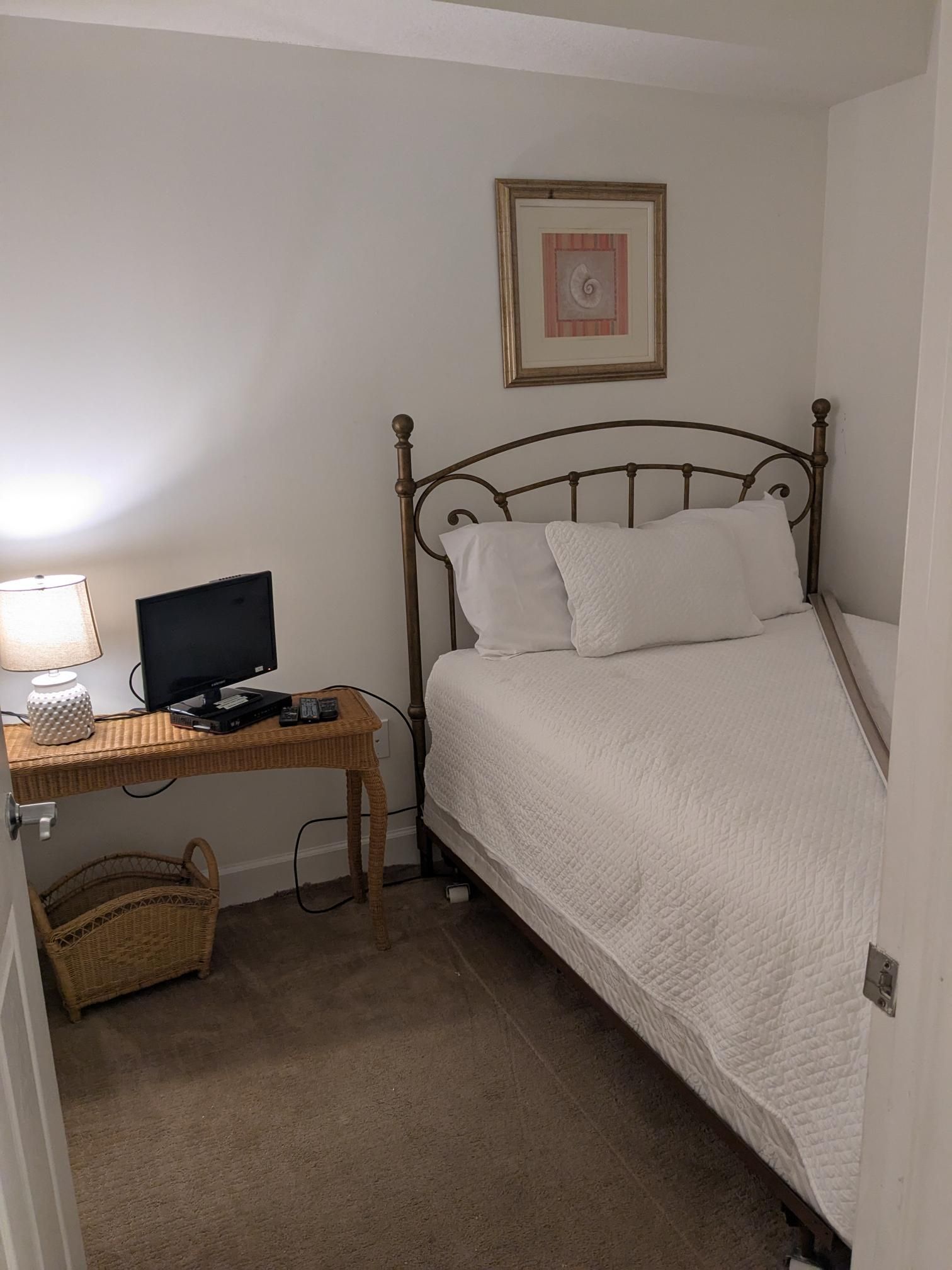 Small bedroom with a bed, desk, and a lamp.