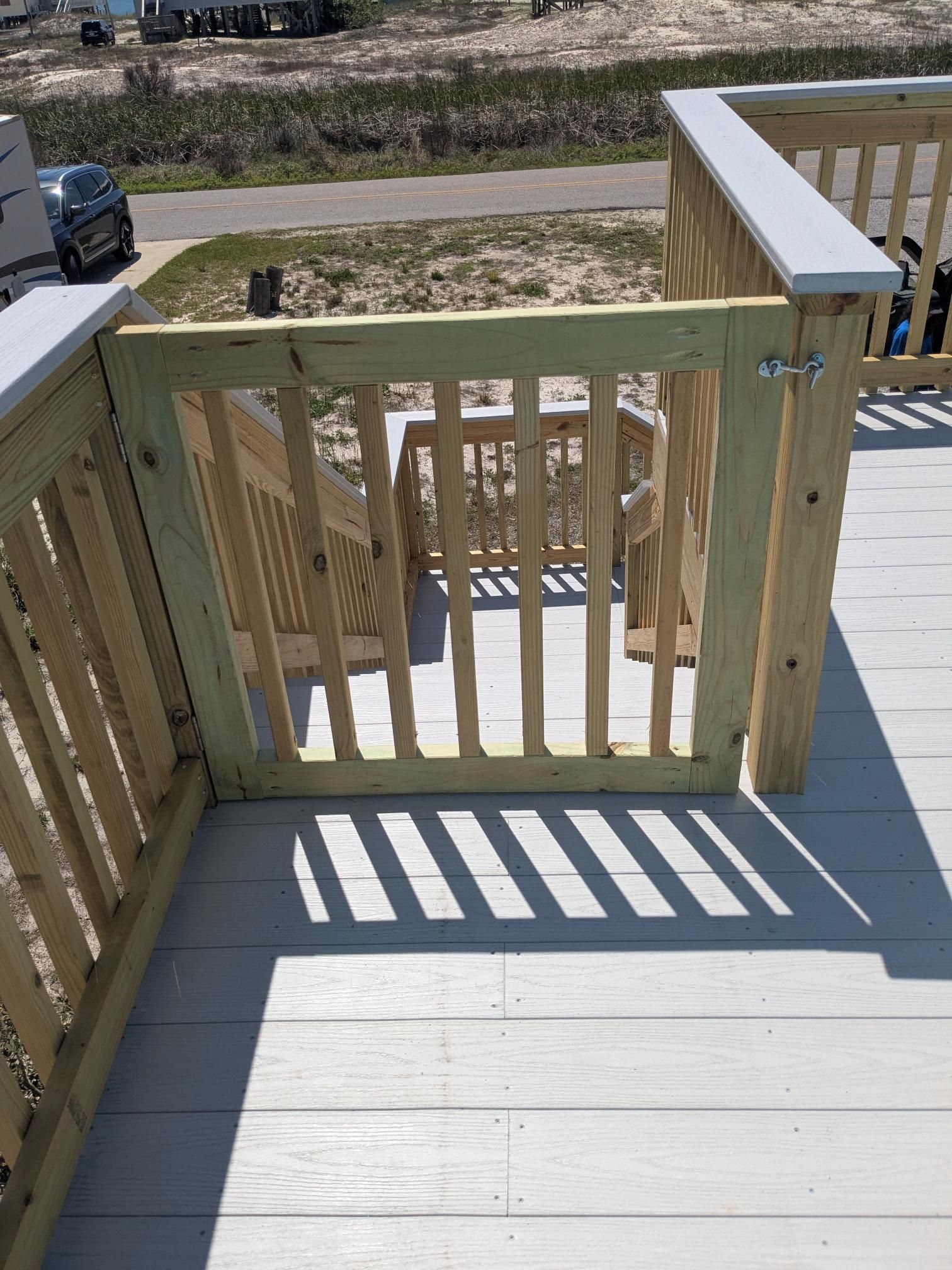Wooden deck with a gate; sunlight casts shadows.