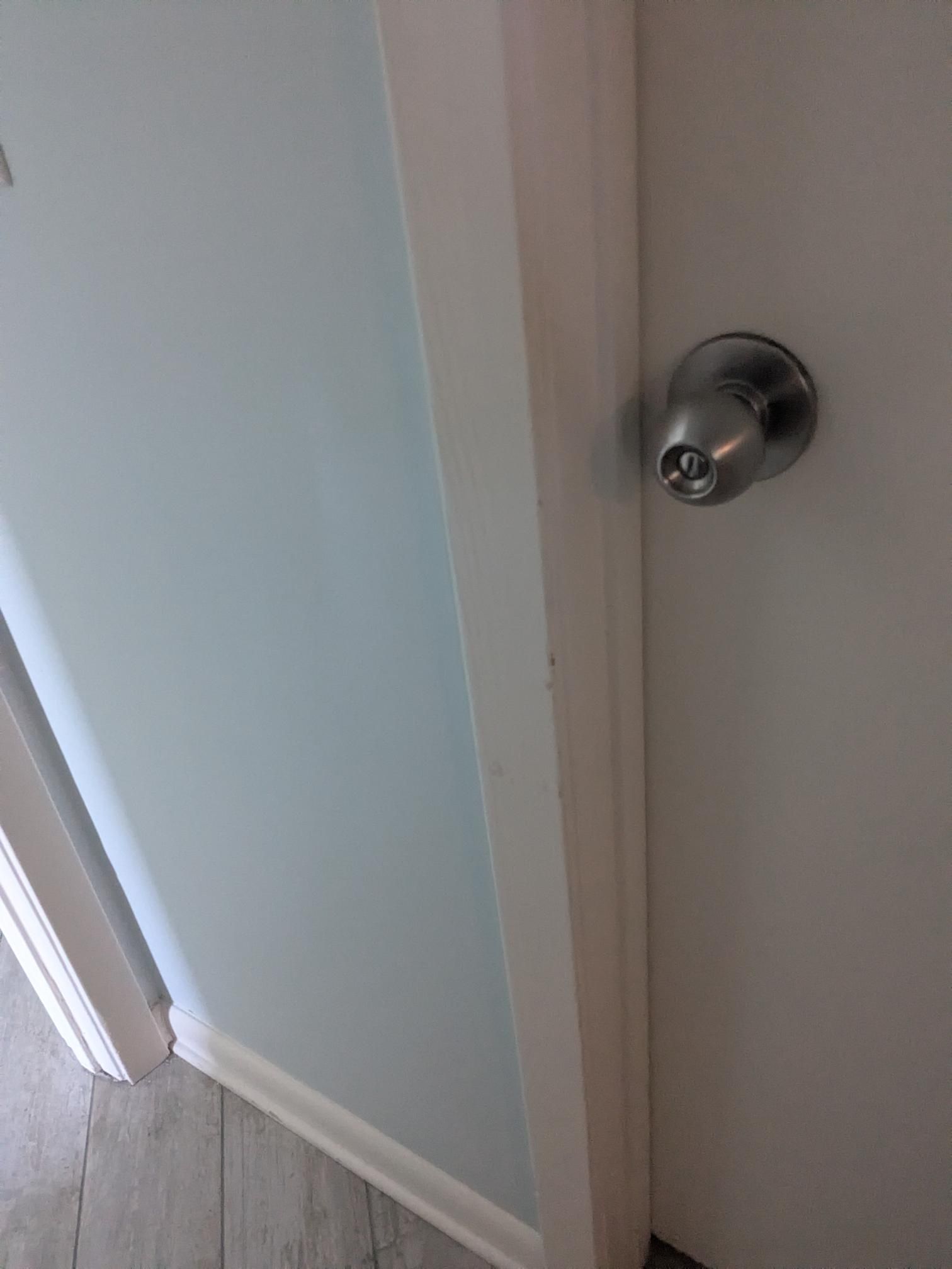 Doorframe with silver doorknob, white trim, and light blue wall.