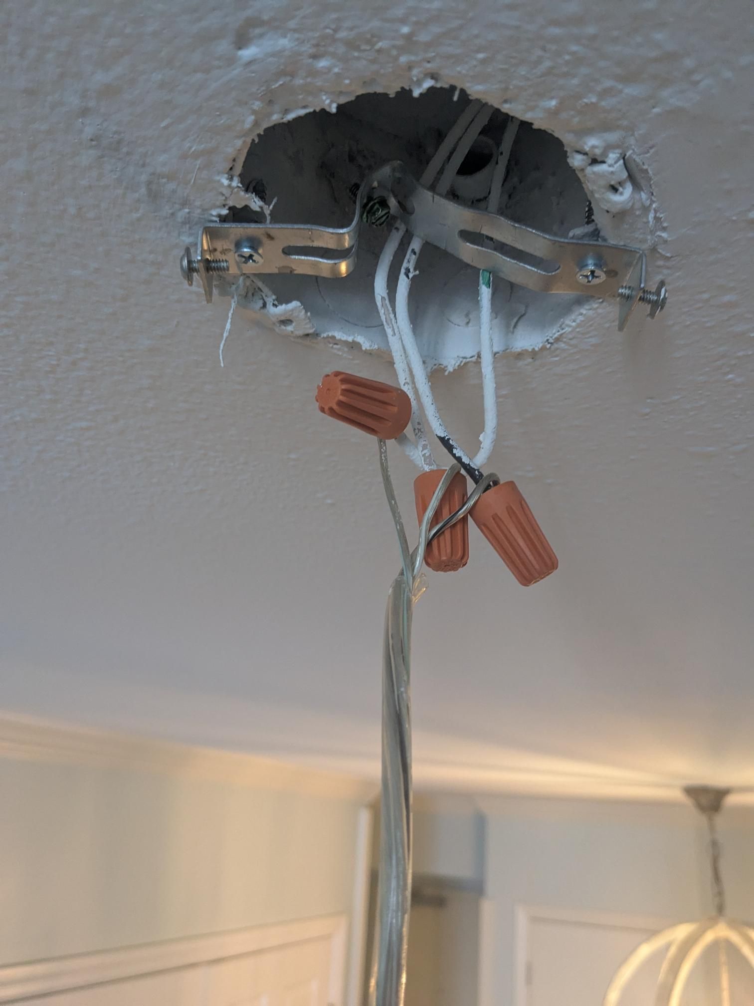 Ceiling wiring with exposed wires and wire connectors, ready for a light fixture.