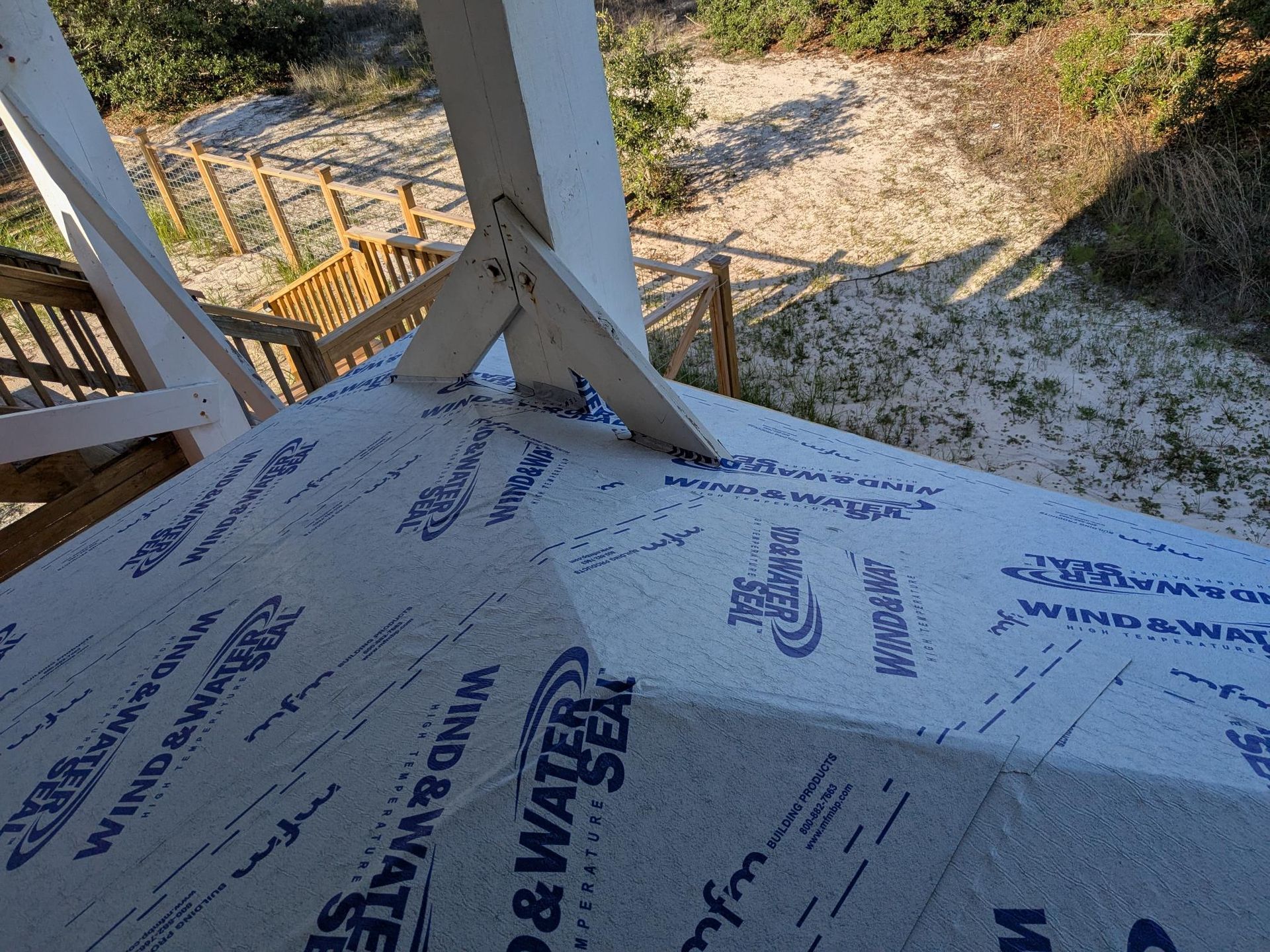 Rooftop with wind and water seal, wooden beams, stairs, and sandy ground.