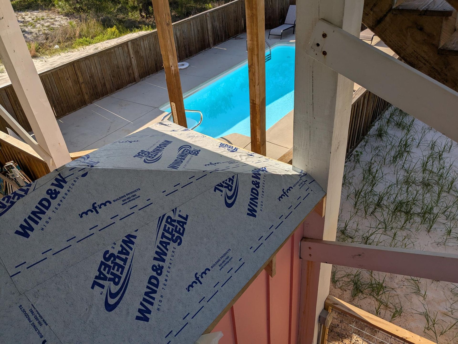 Rooftop view of a pool, with wind and water seal material on a corner roof section.