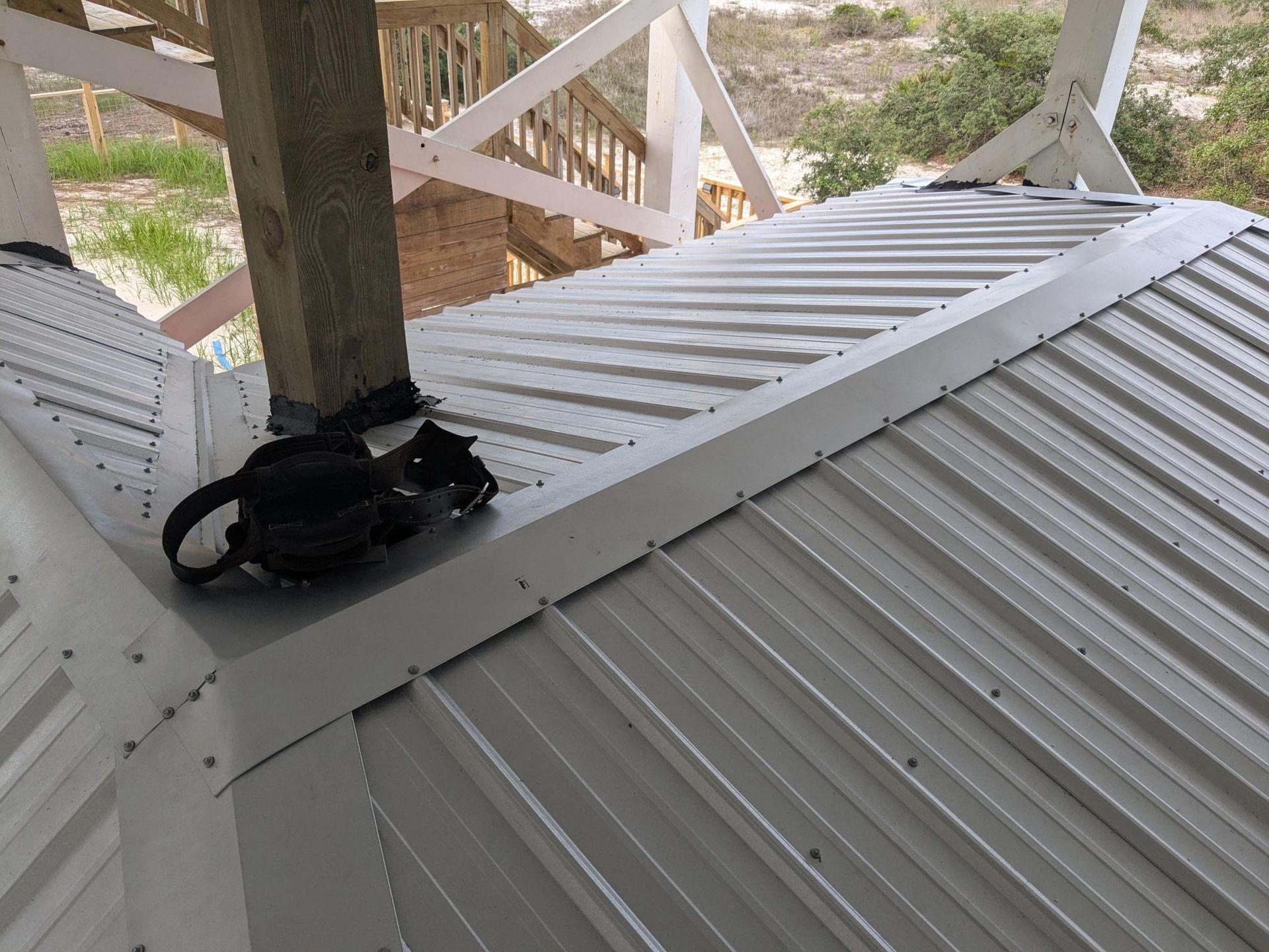 Metal roof with white trim and wooden support post.
