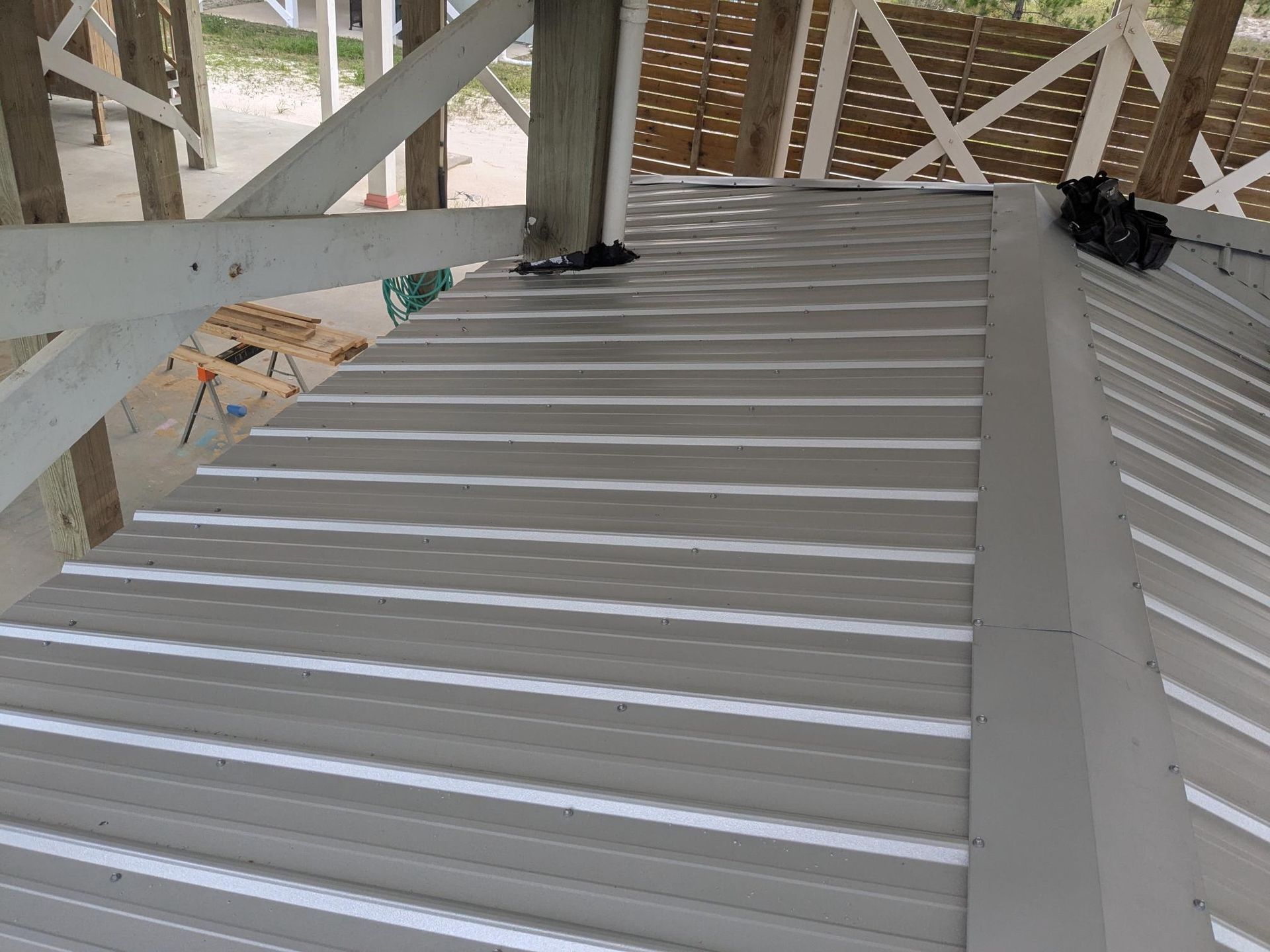 Metal roof on a white gazebo. Gray corrugated panels with white beams and supports.