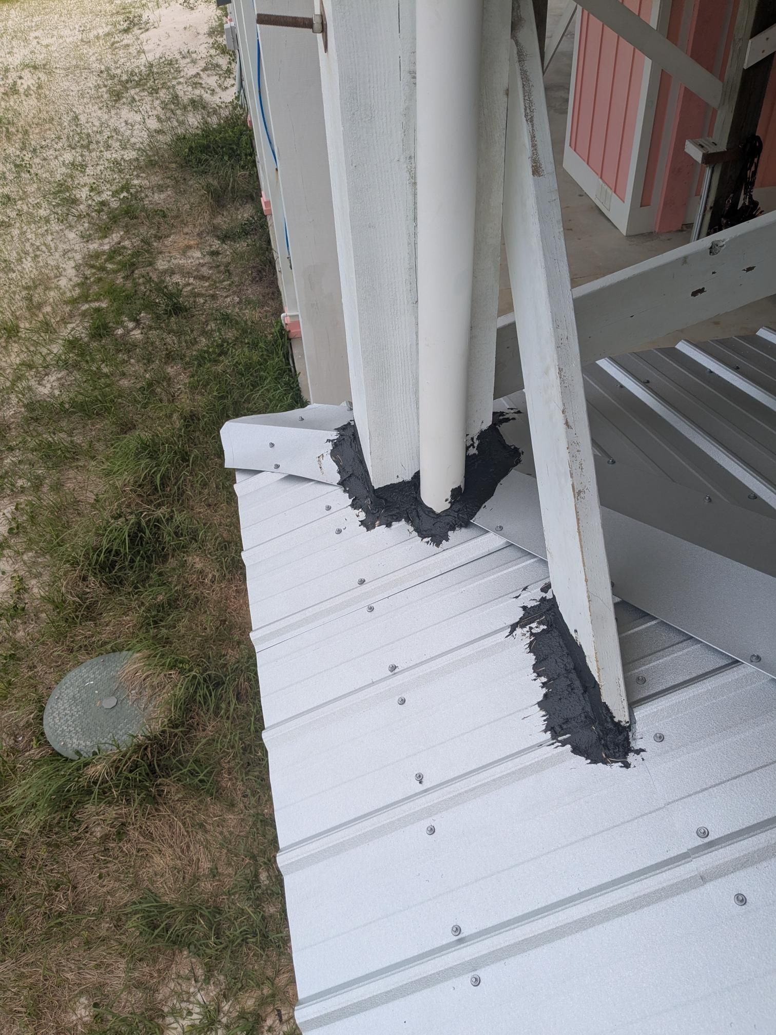White metal roof with gray sealant around support posts and pipes.