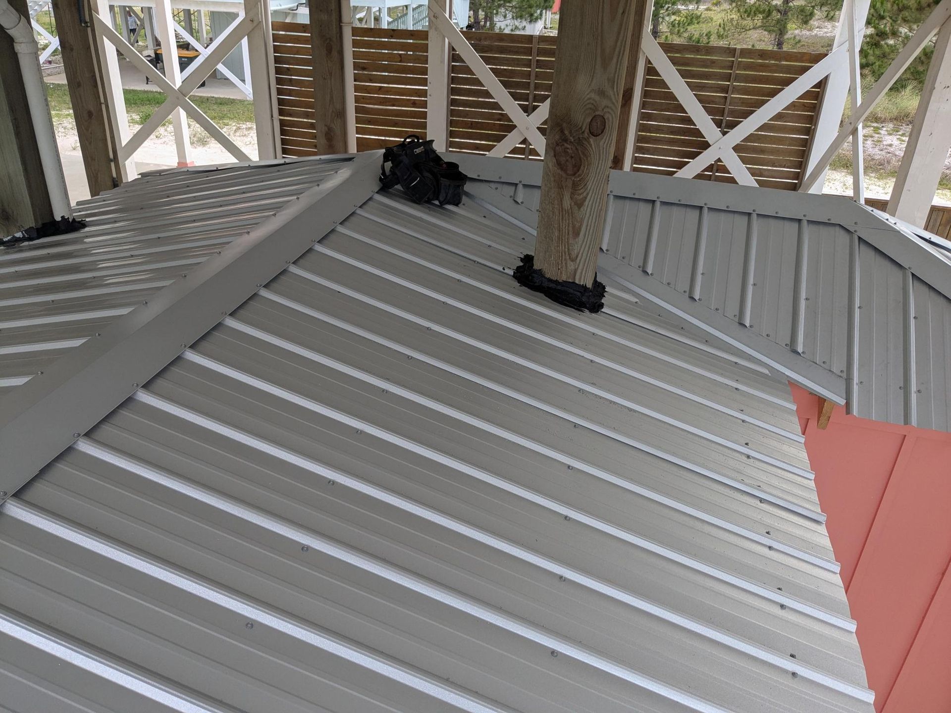 Gray metal roof with a tree trunk rising through it, set on a white gazebo.