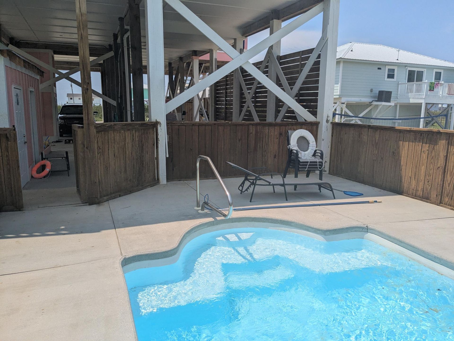 Pool area with a small pool, lounge chair, and house on stilts.