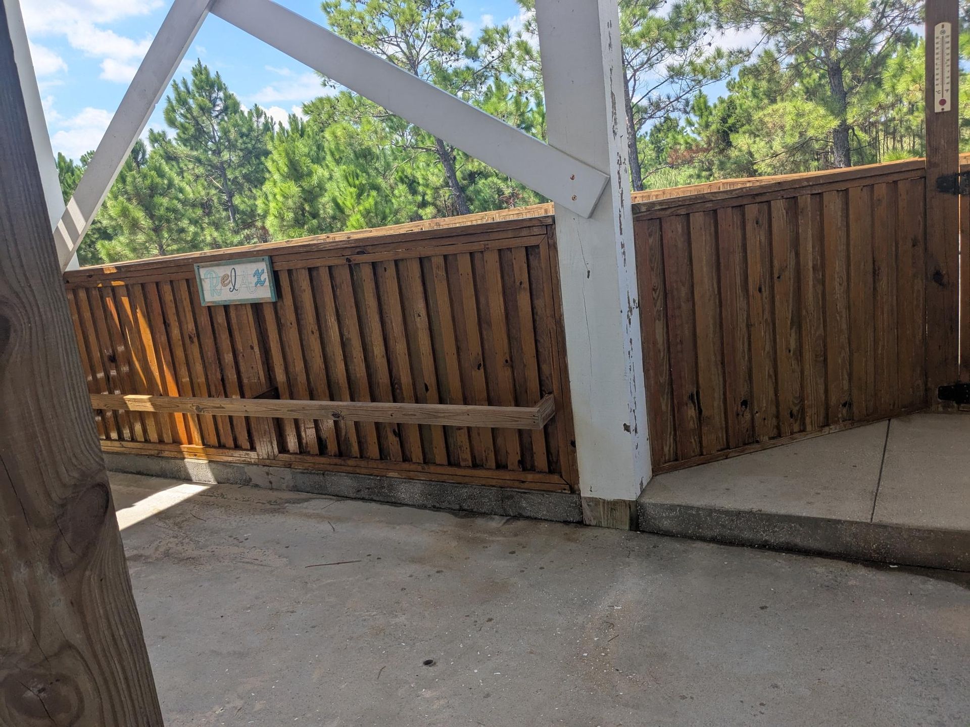 Wooden bridge with a brown wooden fence, white support beams, and a concrete floor.