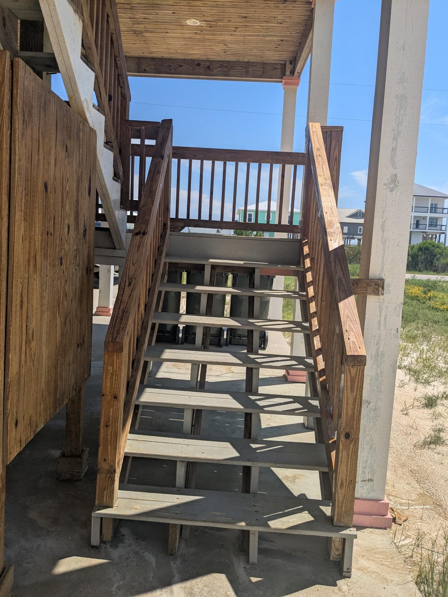 Wooden outdoor staircase leading up, with railing. Brown, gray, and light blue colors.