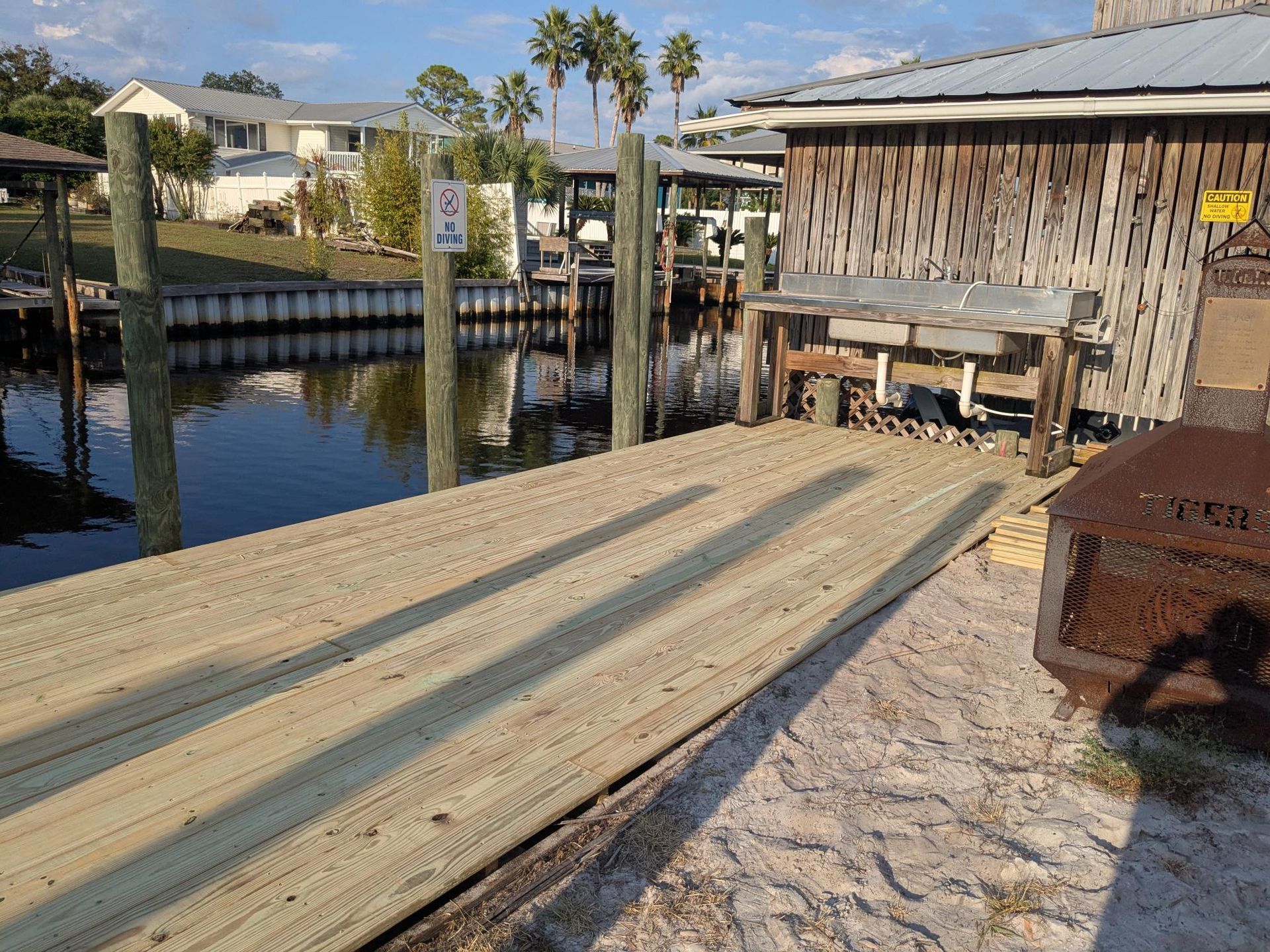 A wooden dock with a ramp leading to a weathered building on a waterway.