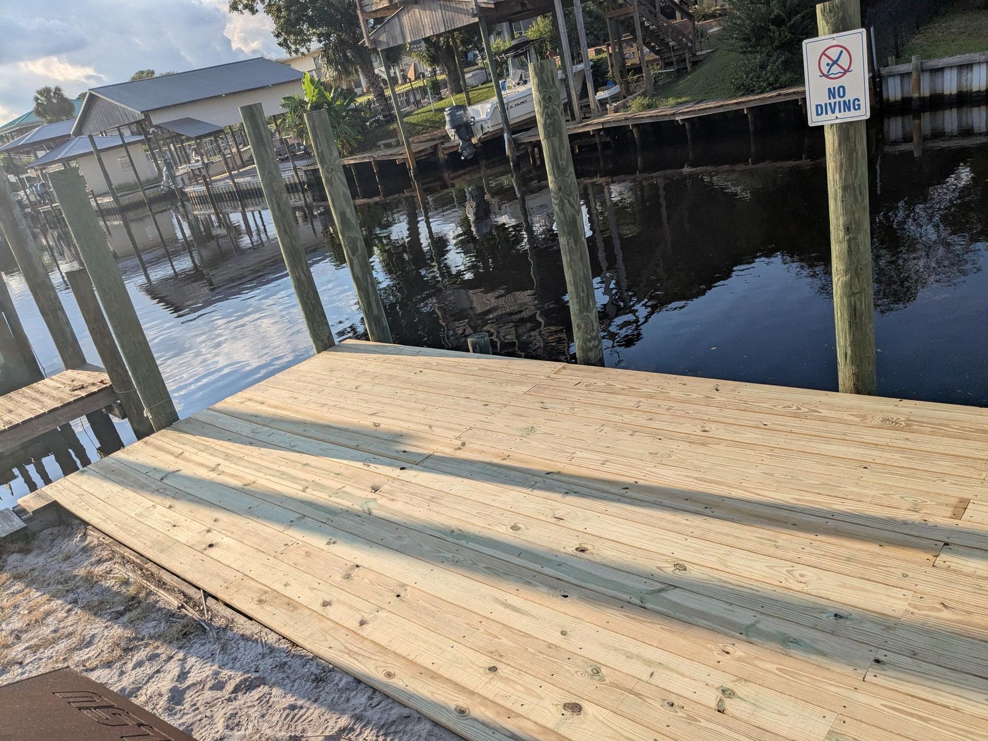 Wooden dock with fresh planks extending toward canal water.