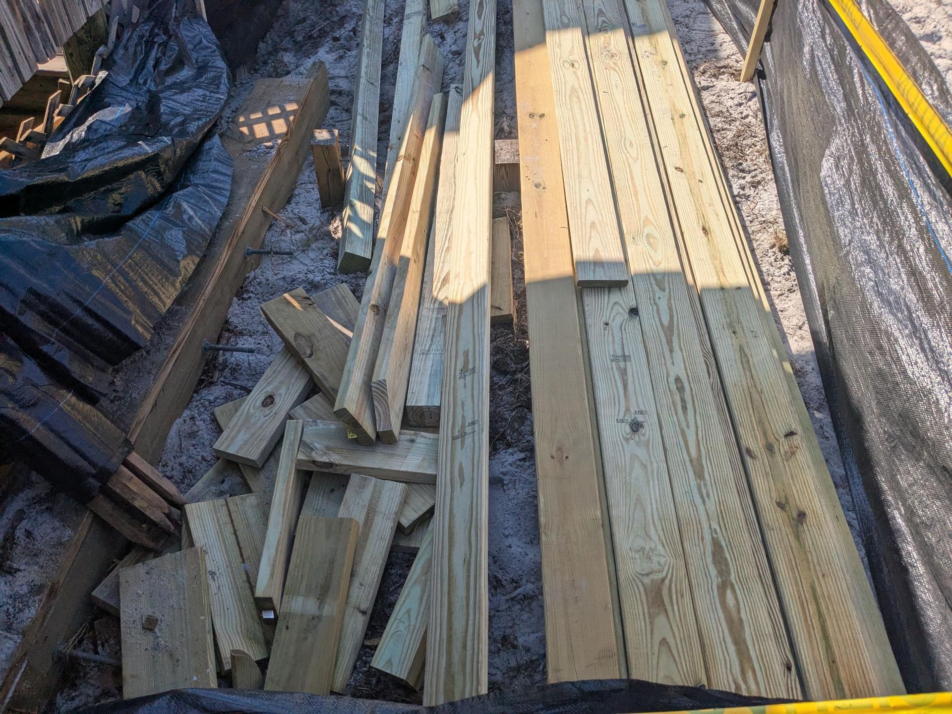 Wooden planks and pieces of lumber on the ground outdoors, likely a construction site.