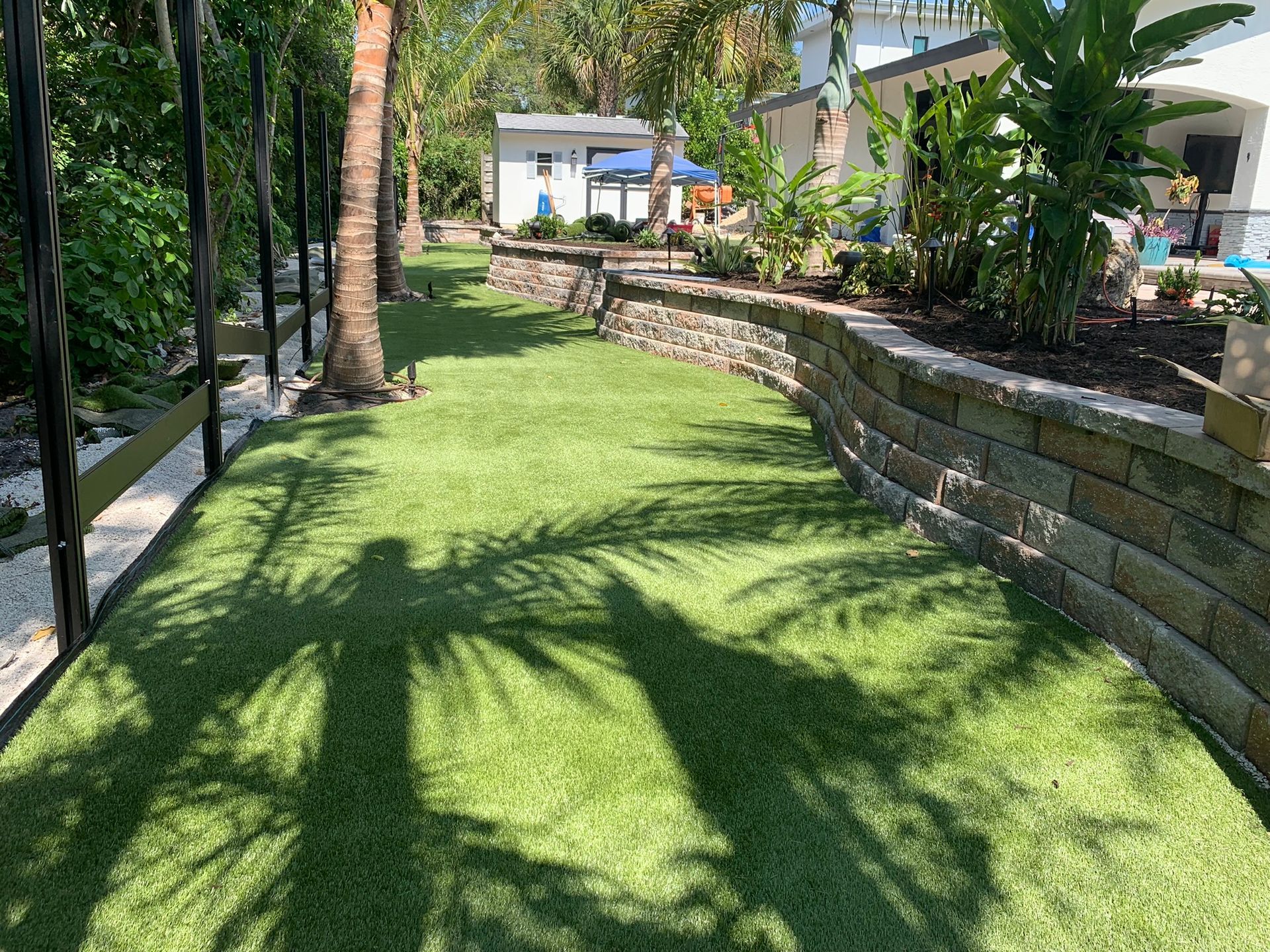 Artificial turf installation with stone retaining wall at a Cherokee Park home in Sarasota